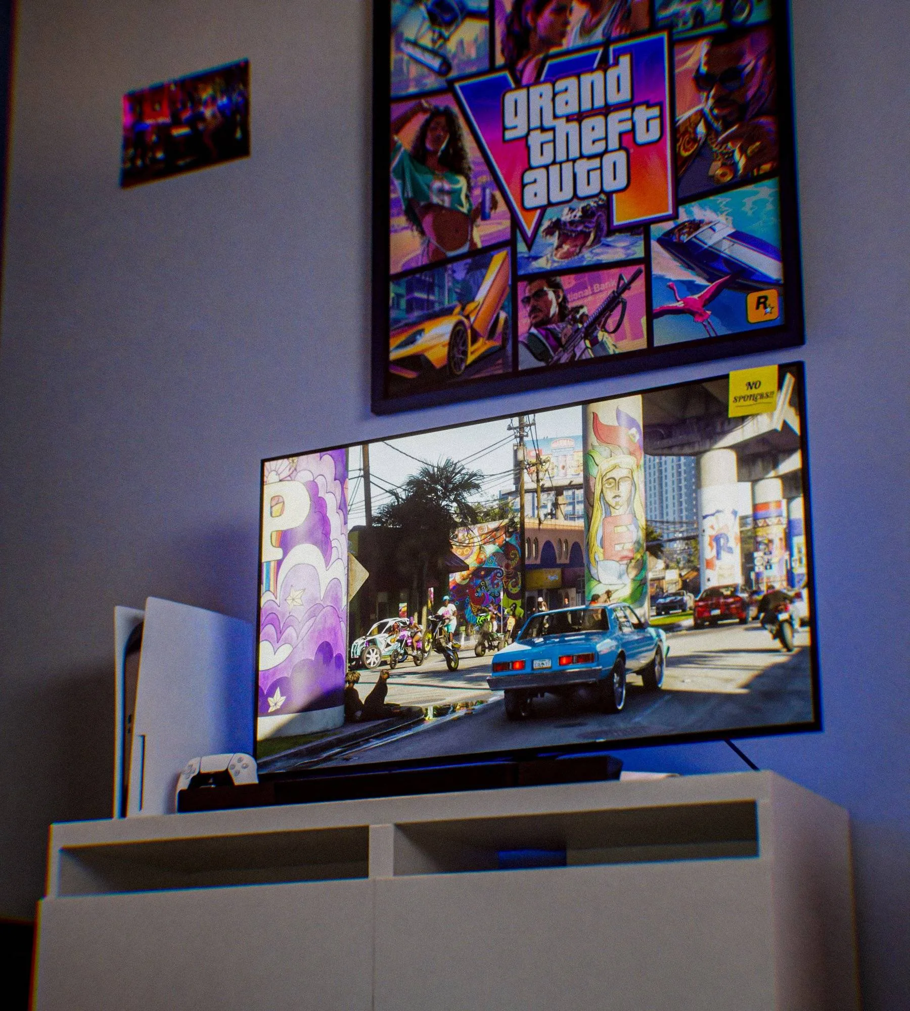 A TV showing an image of GTA VI, under the game’s poster, next to a PlayStation 5.