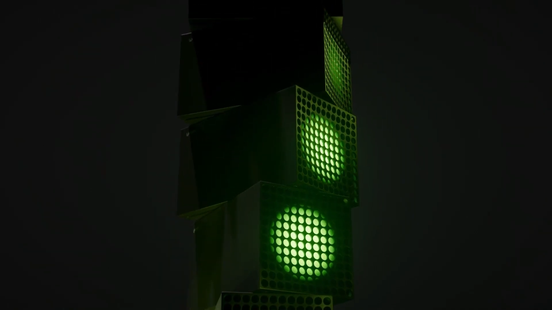 Tour de consoles Xbox empilées, avec leurs grilles éclairées de vert.